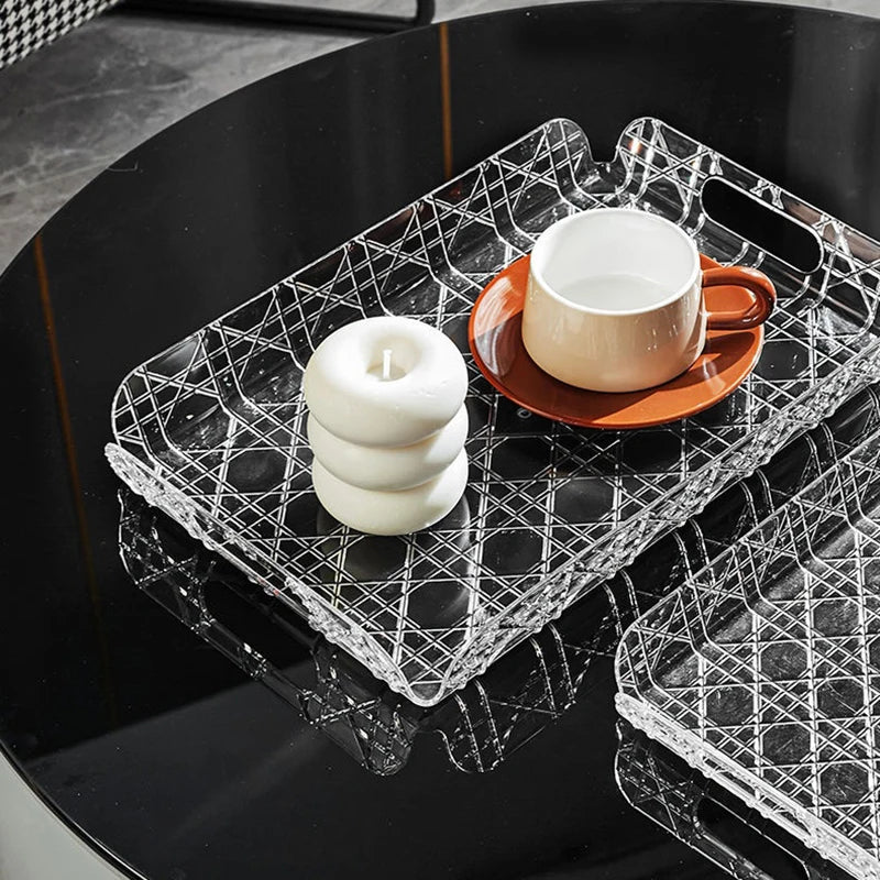 Clear geometric plastic tray displaying a cup and stacked candles on a black table