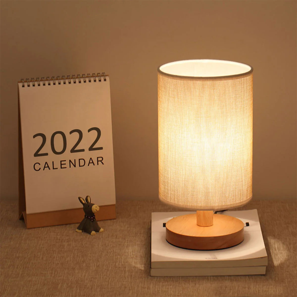 Cylinder table lamp with linen shade on a desk beside a standing calendar