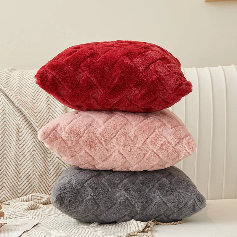 Stack of three plush throw pillow covers in red, pink, and gray on a sofa
