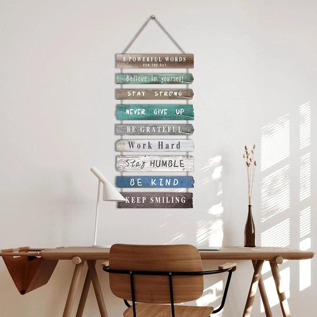 Wooden rectangular motivational wall sign with positive words hanging above a desk in a cozy home office
