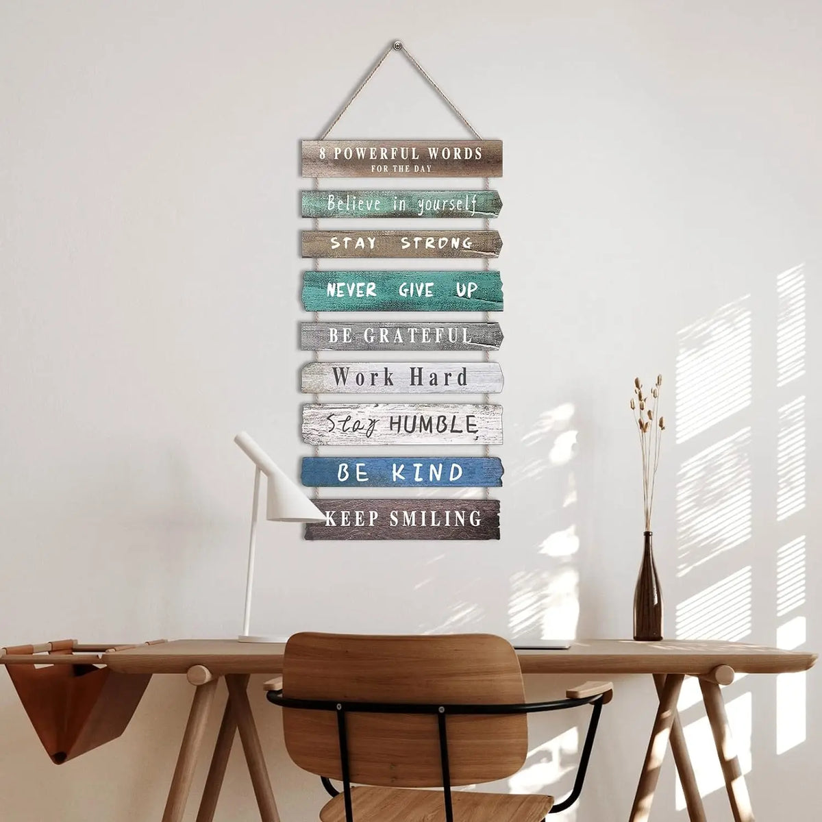Wooden rectangular motivational wall sign with positive words hanging above a desk in a cozy home office