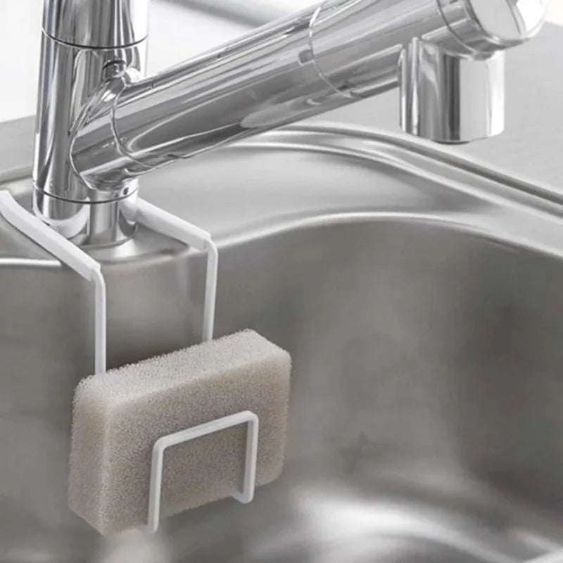 White metal sponge holder mounted on a kitchen faucet holding a sponge