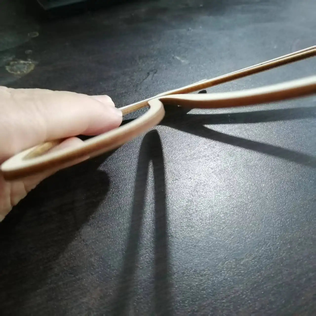Side view showing 3mm thickness of a wooden butterfly wall accent held in hand