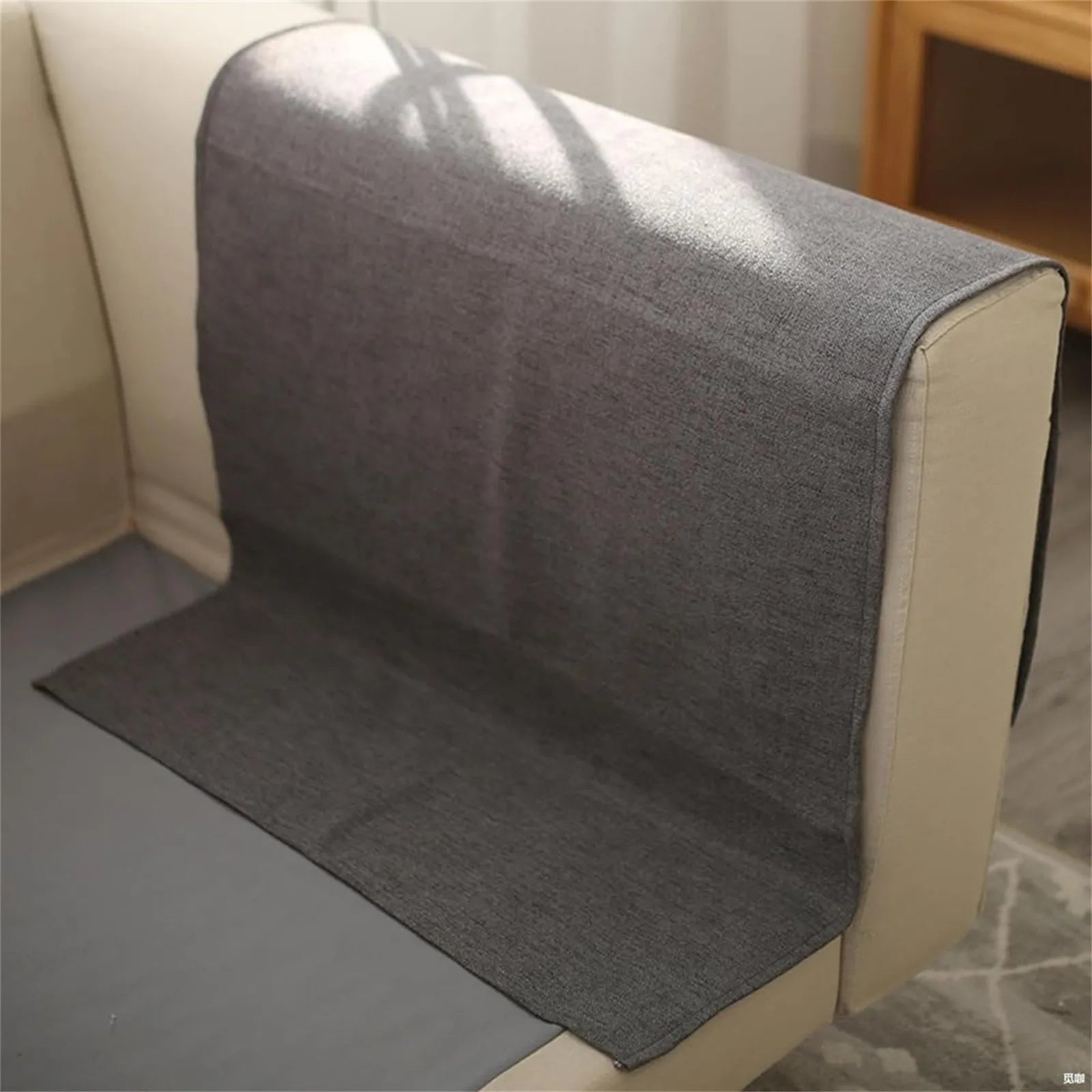 Gray fabric armrest organizer laid flat across sofa arm and seat for installation