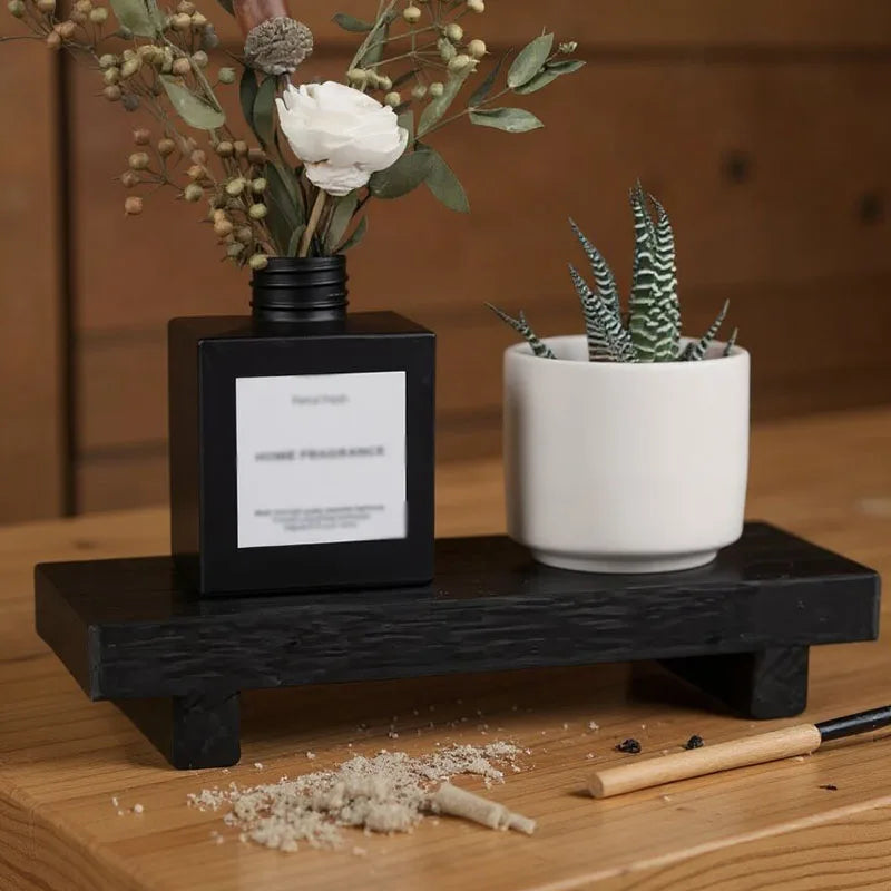Black wooden tray holding vase and succulent, shown on wood surface beside incense