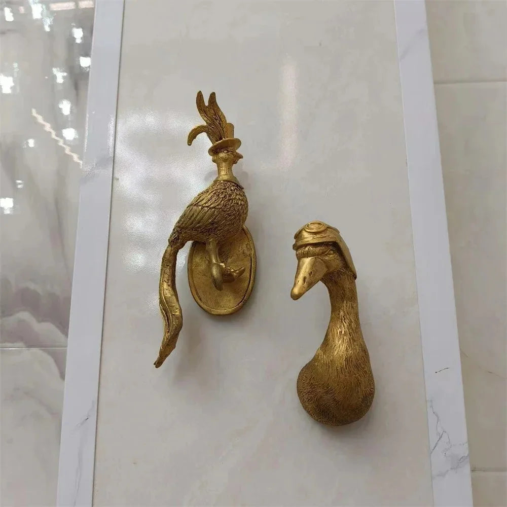 gold bird wall hook and gold duck wall hook mounted vertically on a tiled background