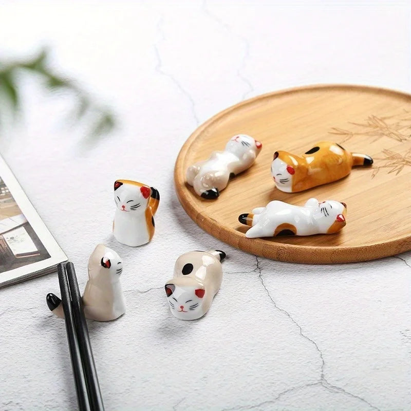 six ceramic cat chopstick holders displayed on a round wooden tray