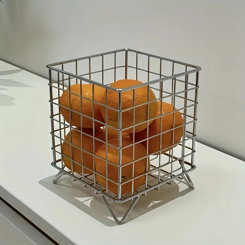 Silver metal grid storage basket with oranges on a white countertop