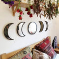 Moon phase acrylic wall mirror set displayed above a cozy bed with boho pillows