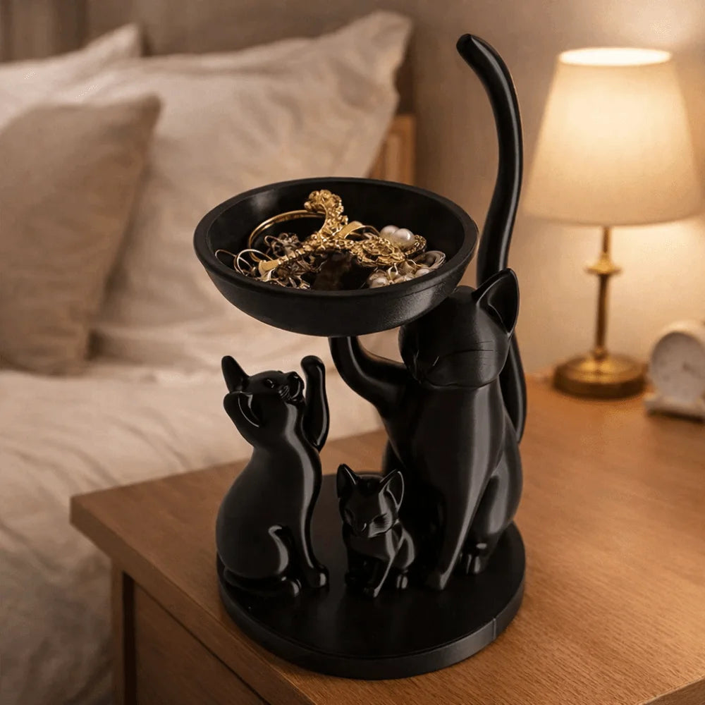 Black cat family shaped jewelry tray on a bedside table with jewelry inside