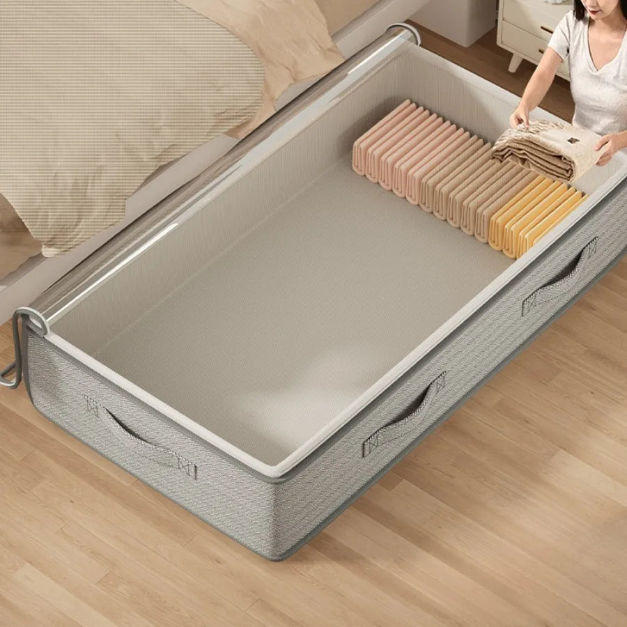 Empty foldable under-bed storage bin in light green, with handles, shown as a person adds folded clothes