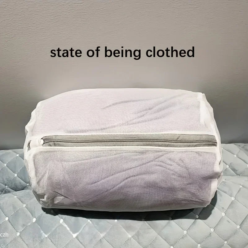 White mesh laundry bag with zipper, holding clothing, sitting on a quilted surface