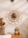 Round woven rattan wall mirror with flower design hanging in cozy room