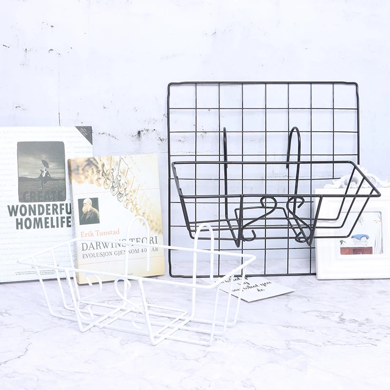 Black wire hanging basket attached to grid wall, white basket placed beside, with home decor books