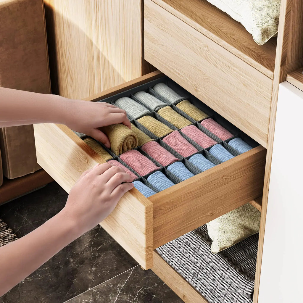 Hands placing a rolled sock into a fabric drawer divider filled with sorted socks