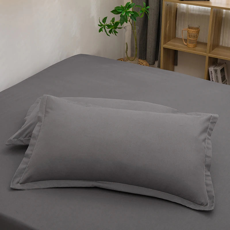 Solid color grey pillowcases on a neatly made bed in a bedroom