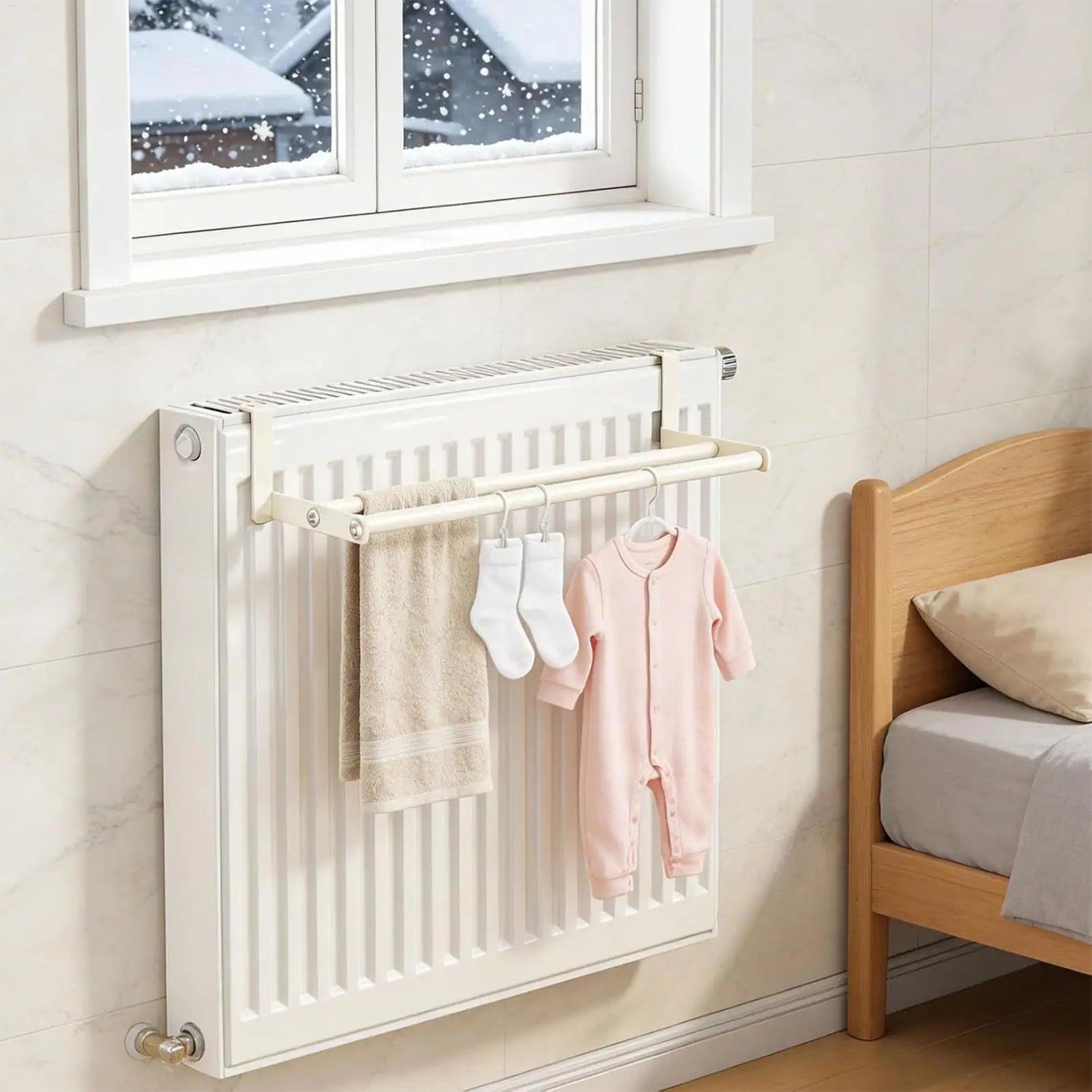 Wall-mounted drying rack installed over a bedroom radiator with towel, socks, and baby outfit drying
