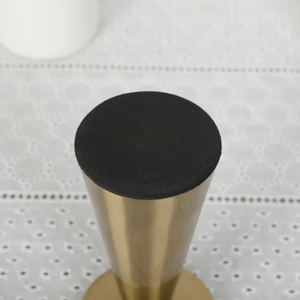 Bottom view of a gold cone-shaped candle holder showing its soft black protective base.