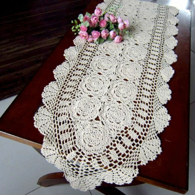Crochet lace table runner with floral motifs on a classic dark wood table, styled with flowers