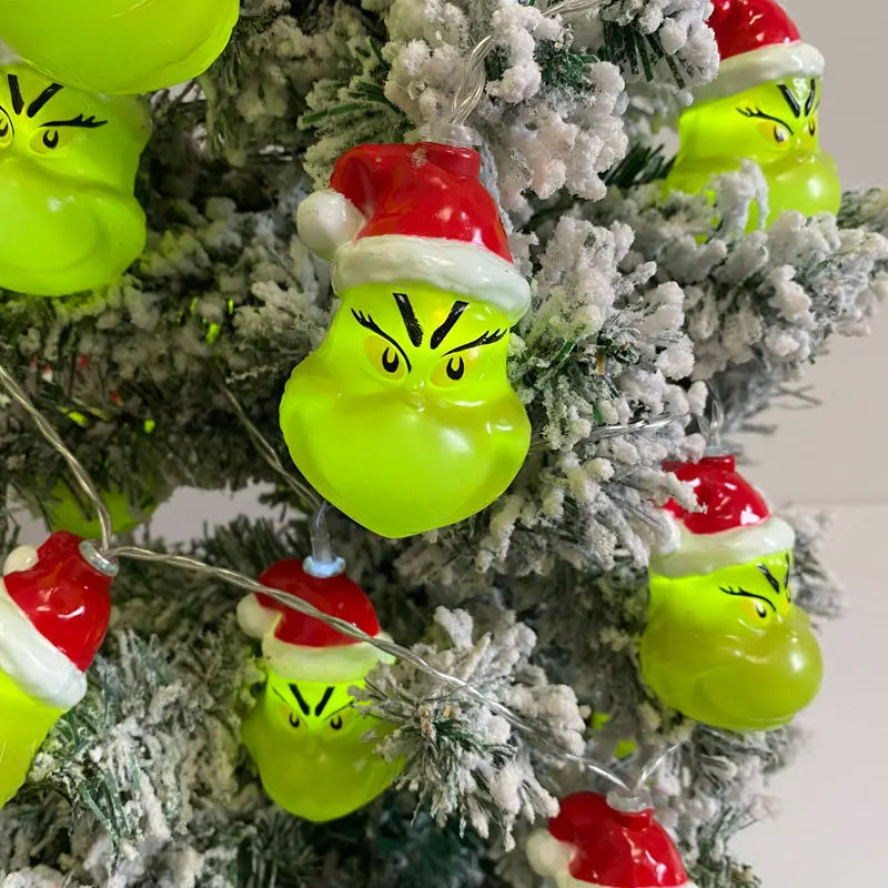 Grinch-inspired string lights wrapped on a snowy Christmas tree