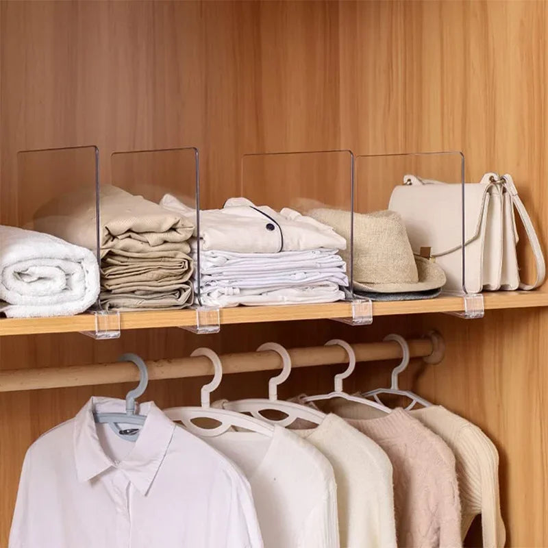Three transparent dividers on a wardrobe shelf separating folded linens, shirts, and handbags above hanging clothes