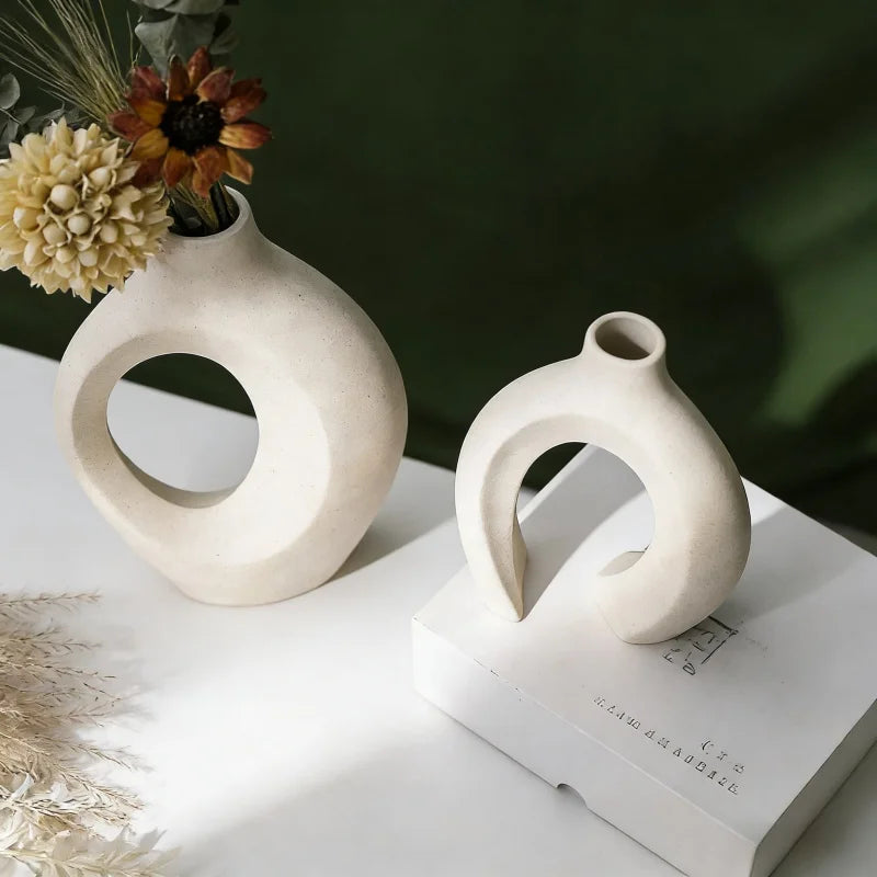 sculptural white resin vases on tabletop and book, styled with flowers