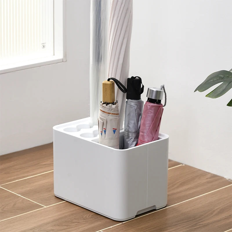 White plastic umbrella stand in entryway holding both long and folding umbrellas