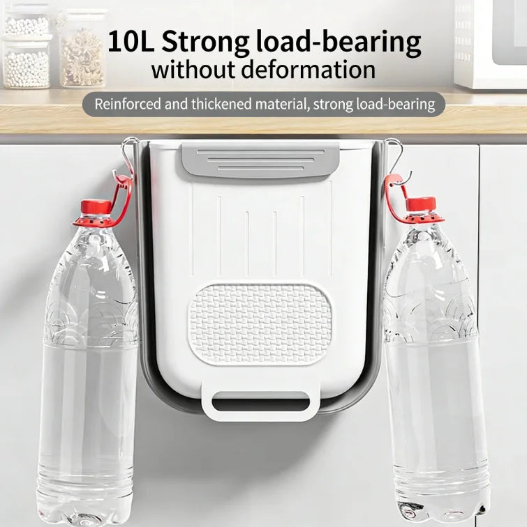 Foldable trash bin hanging on cabinet holding two large water bottles to show sturdiness