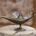 ornate metal incense burner lamp with floral relief, smoke wafting from spout