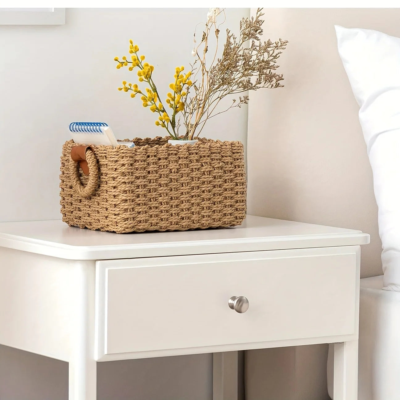 Woven storage basket on a nightstand with flowers and notebooks