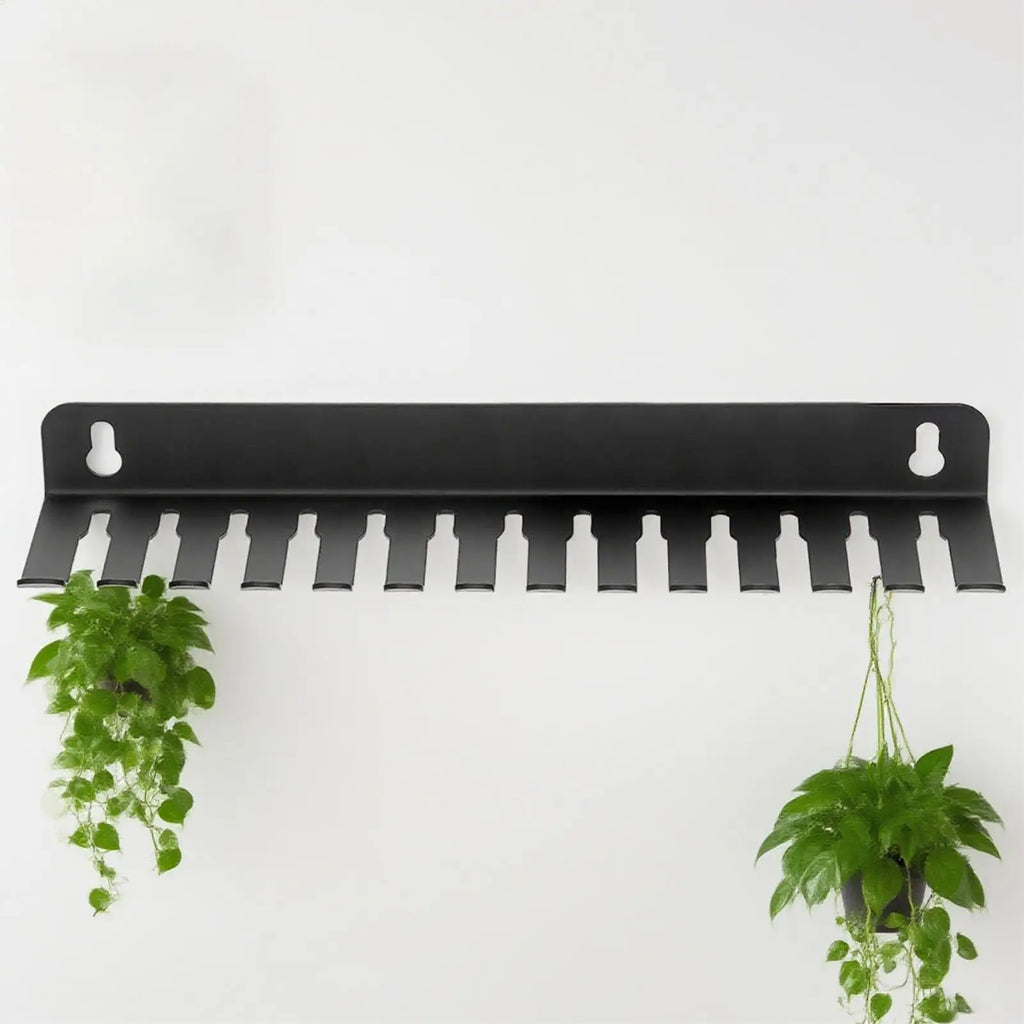 Matte black metal cable organizer with plants hanging from end slots against a white wall