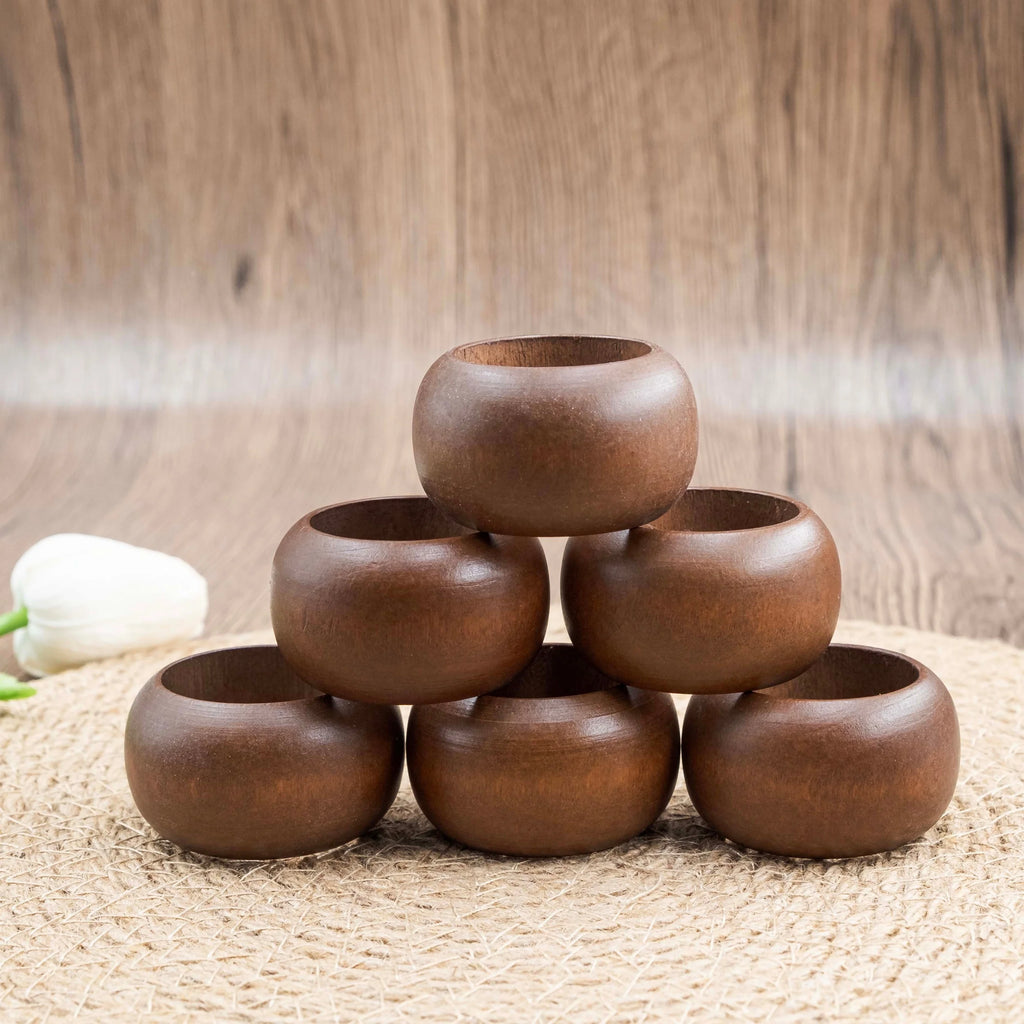 Stack of six round acacia wood napkin rings on a woven placemat with neutral wood background