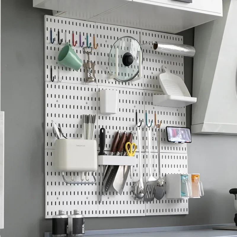 White pegboard wall with assorted plastic hooks, baskets, and holders organizing kitchen utensils and accessories