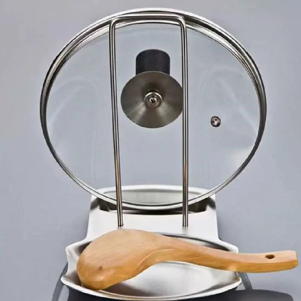Stainless steel pot lid and utensil holder with a glass lid and wooden spoon resting on kitchen counter