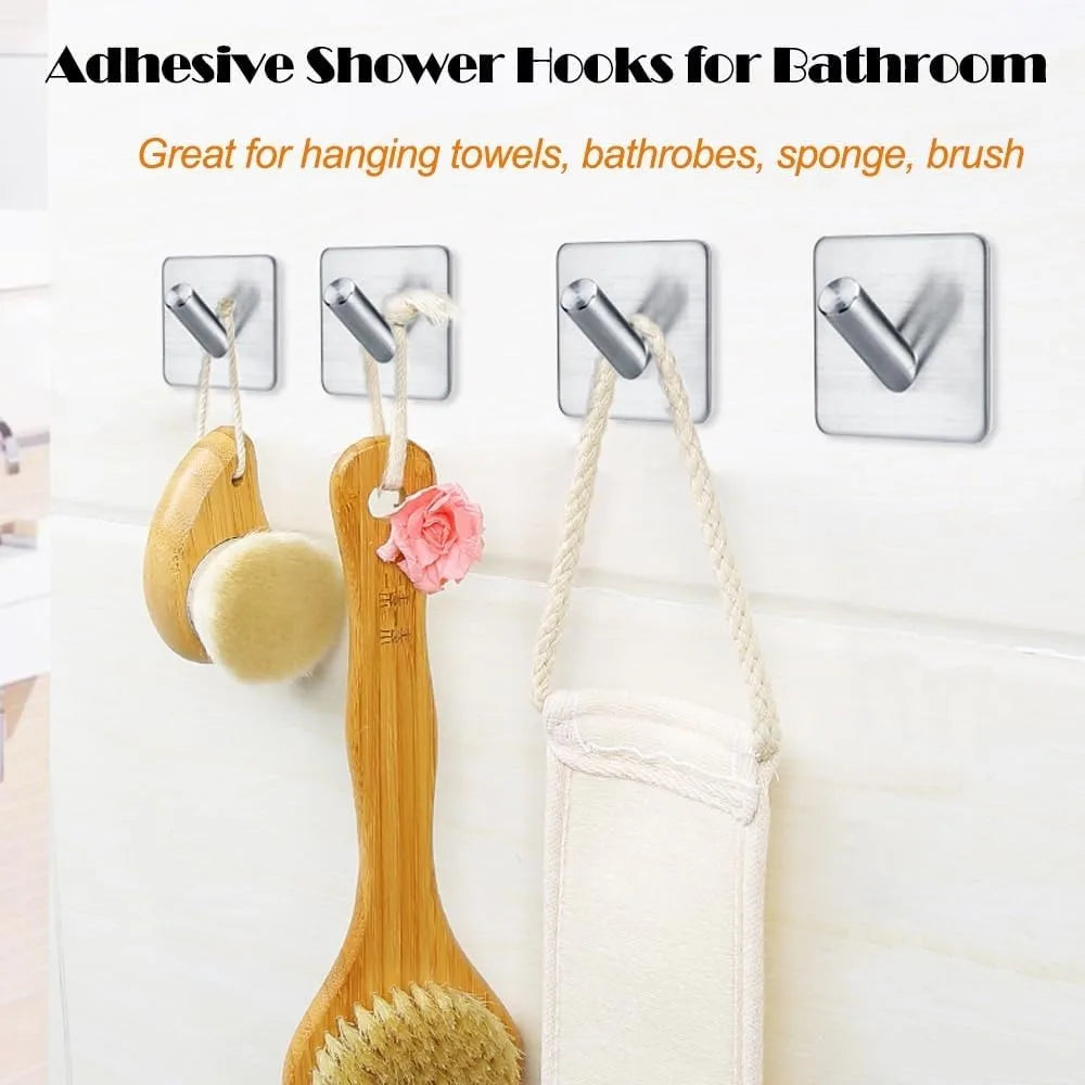 Four stainless steel adhesive hooks on bathroom tile wall holding brushes and a sponge