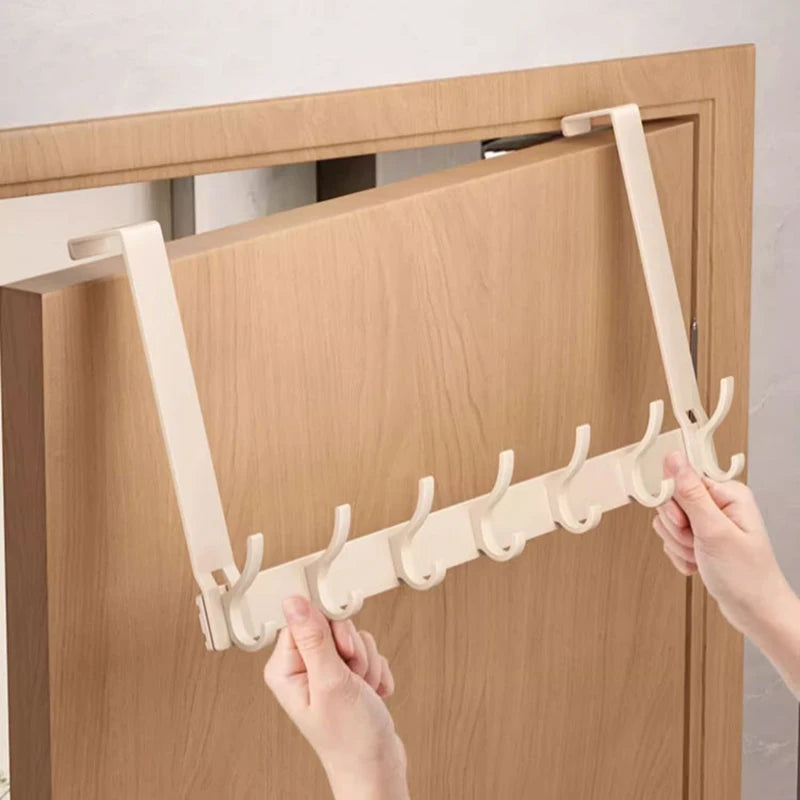 Hands hanging cream aluminum rack with hooks over a wooden door