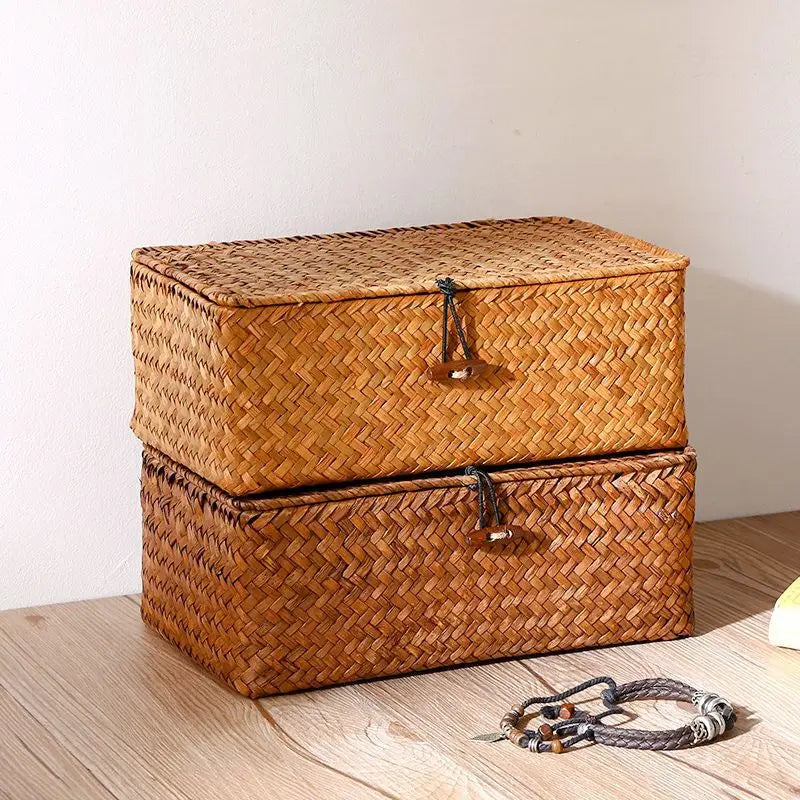 Two stacked rectangular woven bamboo storage baskets with lids on a wooden surface
