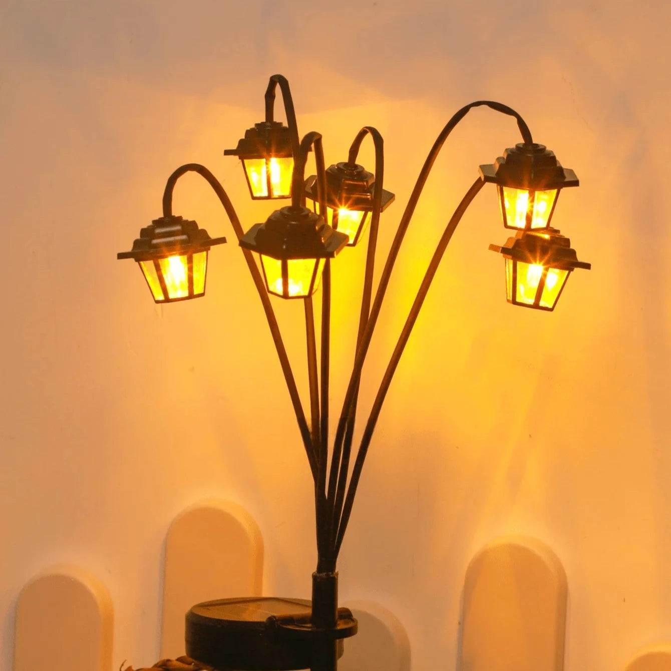 Cluster of solar-powered retro lantern lights glowing against a wall