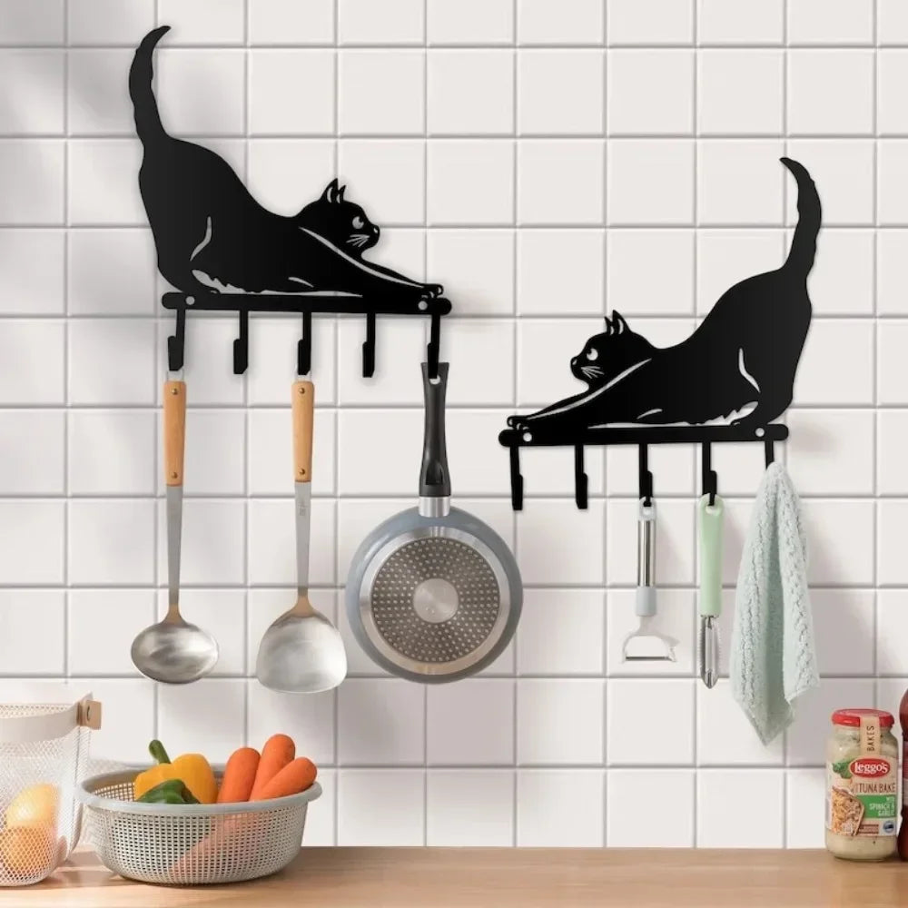 Two stretching cat wall hook racks mounted on a kitchen wall, holding utensils and towels