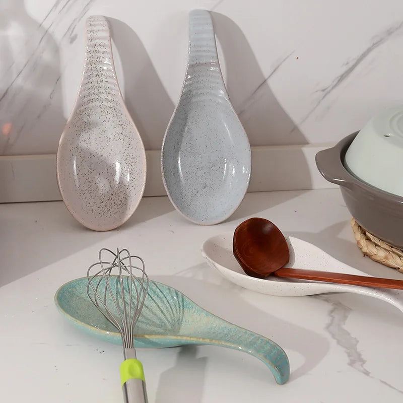 Assortment of speckled ceramic spoon rests on a kitchen counter holding various utensils