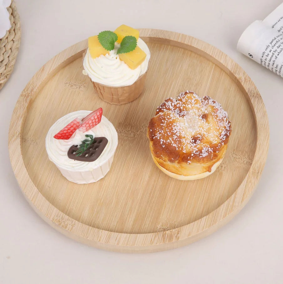 Empty round bamboo tray table with three cupcakes on display