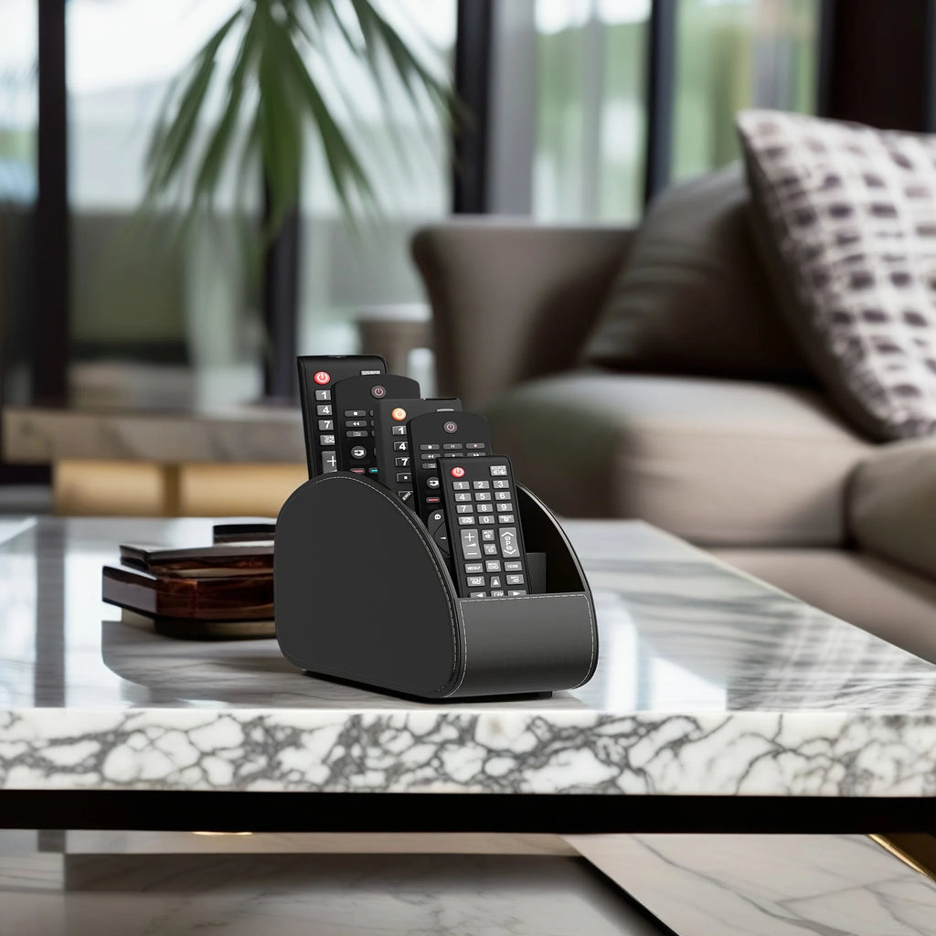 Black remote holder on a marble coffee table with remotes in a modern living room
