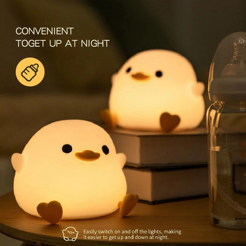 Two duck night lights on books, next to a baby bottle on a nightstand