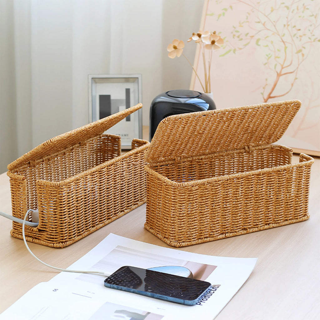 Two hand-woven style cable organizer boxes on a tabletop in a cozy room