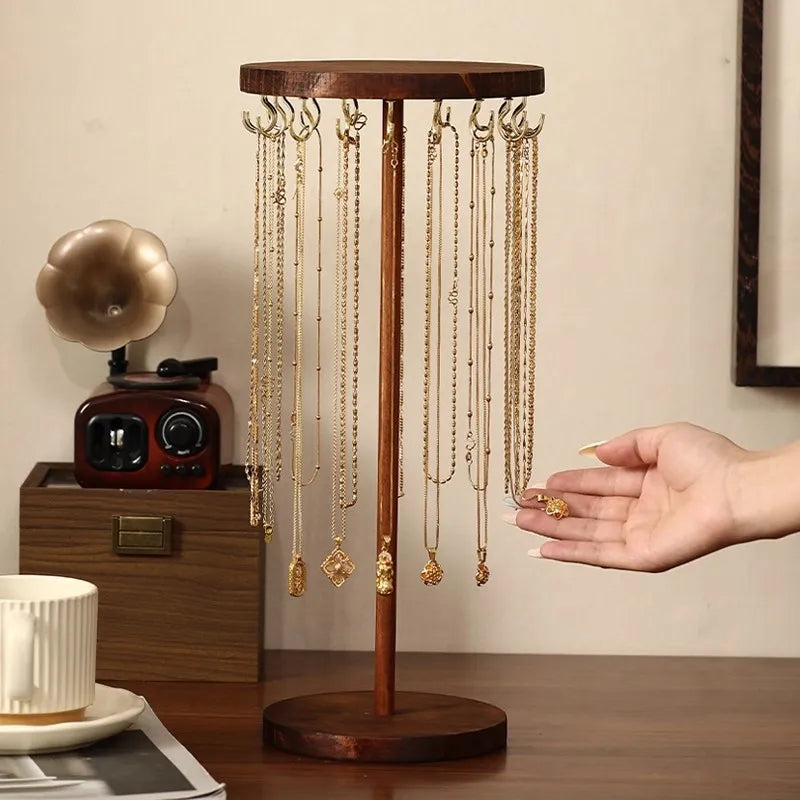 Hand reaching for necklace on walnut wood jewelry organizer stand with hooks