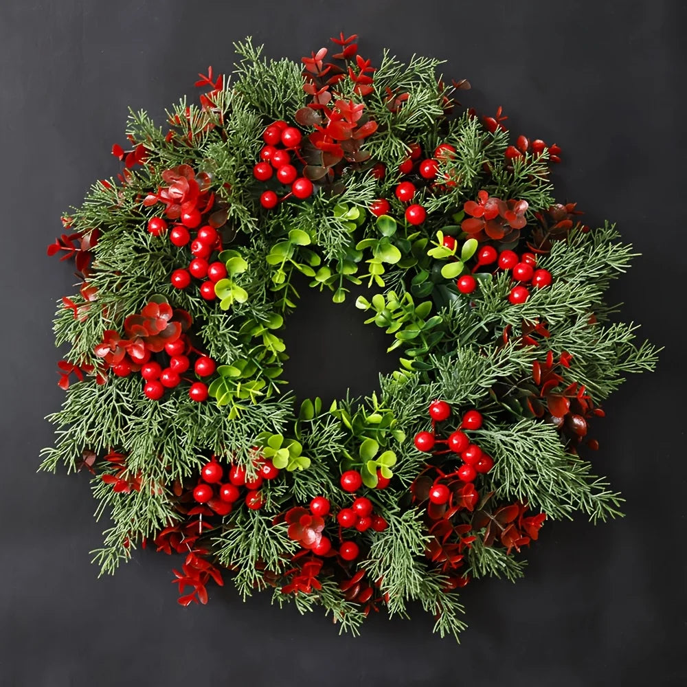 Faux evergreen and red berry holiday wreath against black background