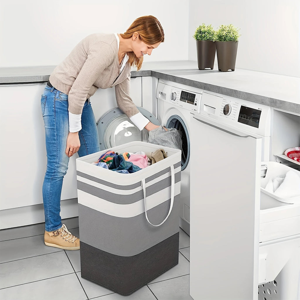 Person loading clothes from a striped rectangular laundry hamper into a front-load washing machine in a modern laundry room