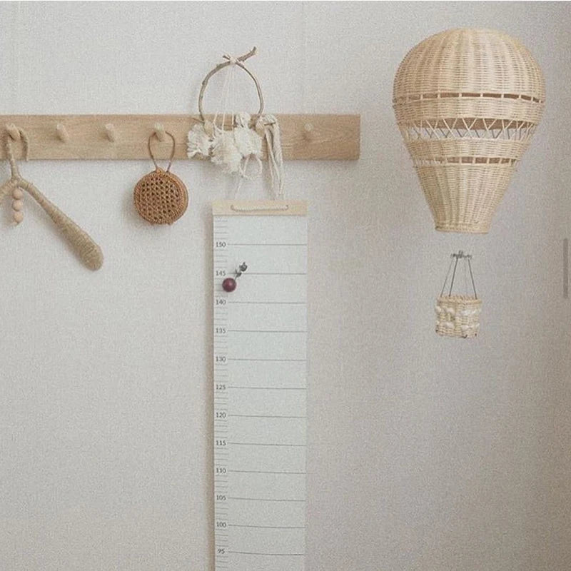 rattan hot air balloon wall hanging next to growth chart in entryway or kids room