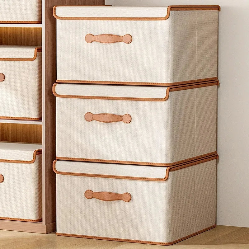 Three beige foldable storage boxes stacked vertically inside a wardrobe closet