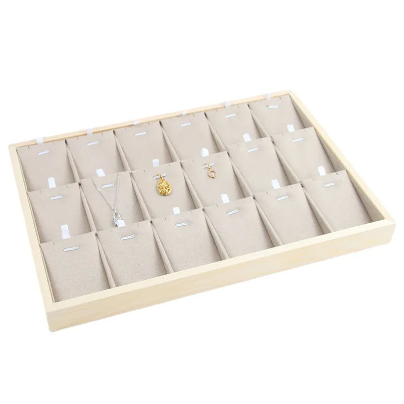 Velvet jewelry tray with divided sections for storing pendants, some holding necklaces and earrings, beige velvet lining